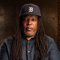 A man with dreadlocks wearing a detroit tigers cap.