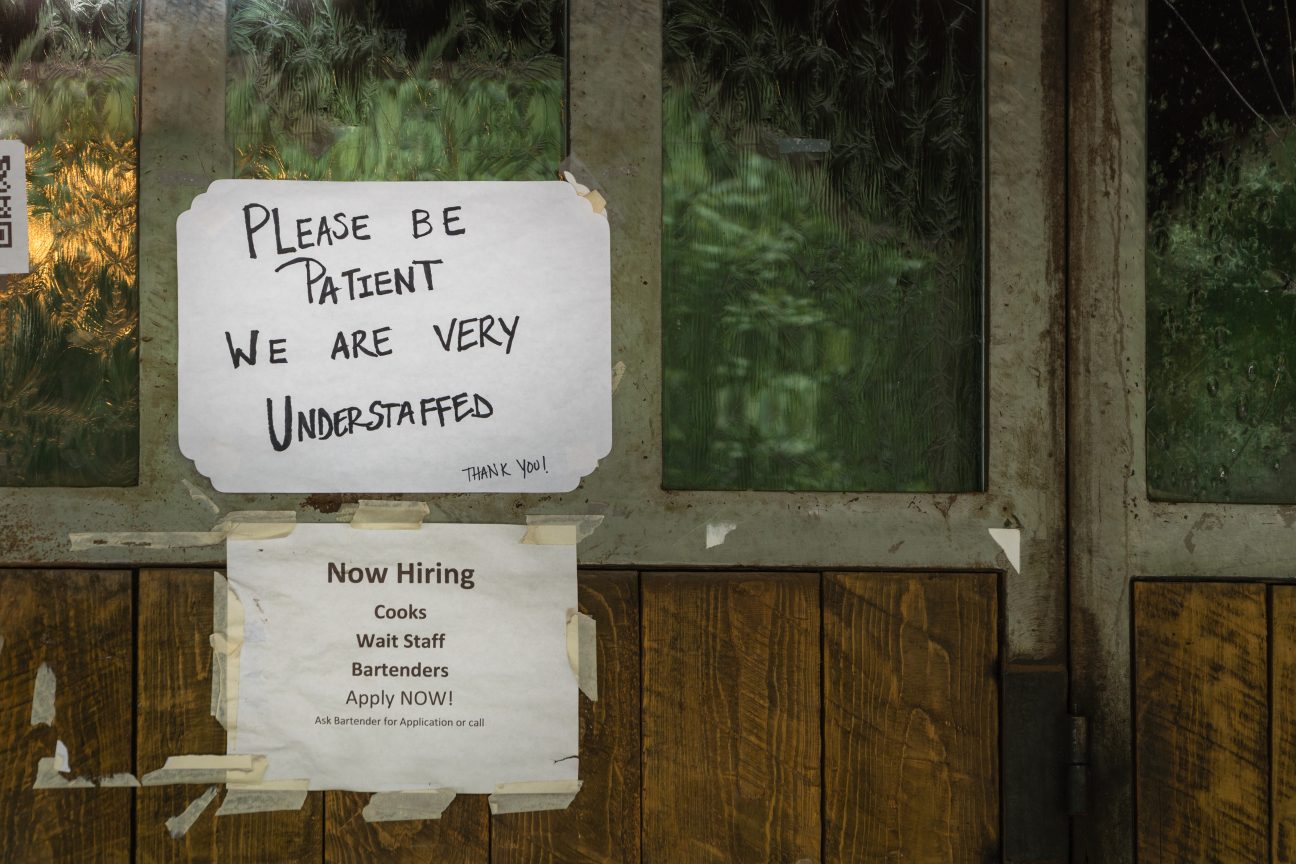 A help wanted sign taped to the window of a local restaurant.