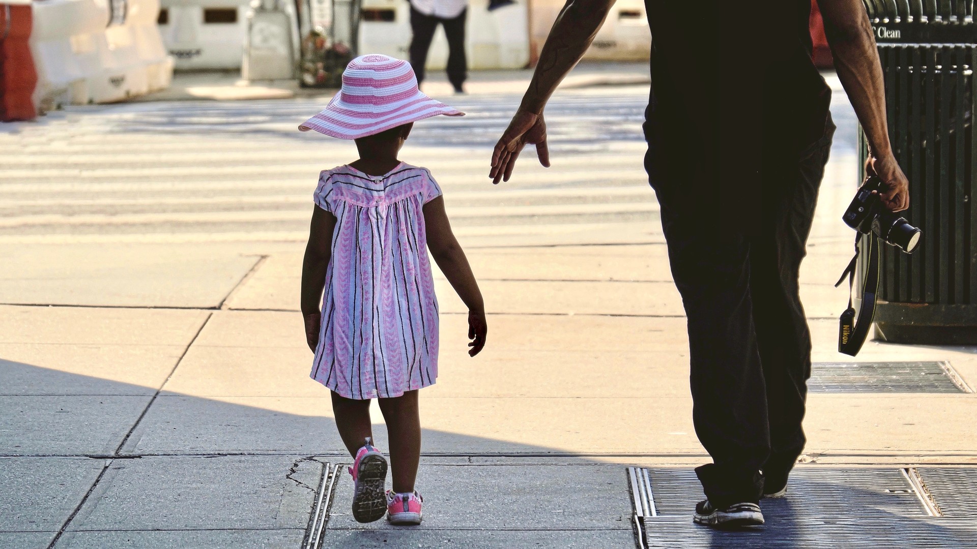 A father holds out his hand for his little girl to hold.