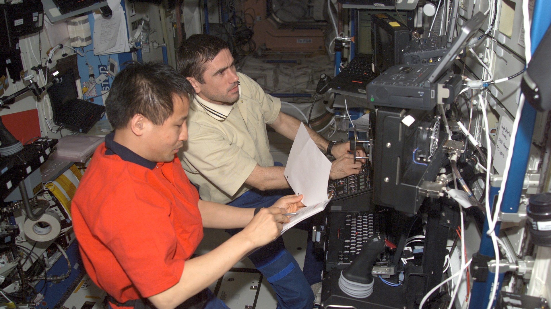 Astronaut Edward T Lu (foreground) and cosmonaut Yuri Malenchenko work the controls of the Canadarm 2 from the Destiny laboratory on the International Space Station.