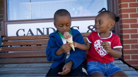 A boy and girl share an ice cream cone