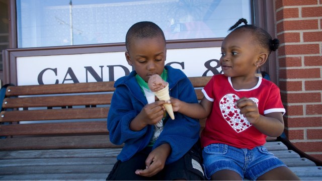 A boy and girl share an ice cream cone