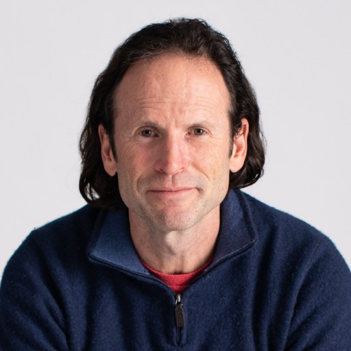 a man with long hair wearing a blue jacket.