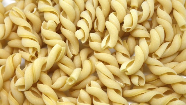 a pile of uncooked macaroni shells on a white surface.