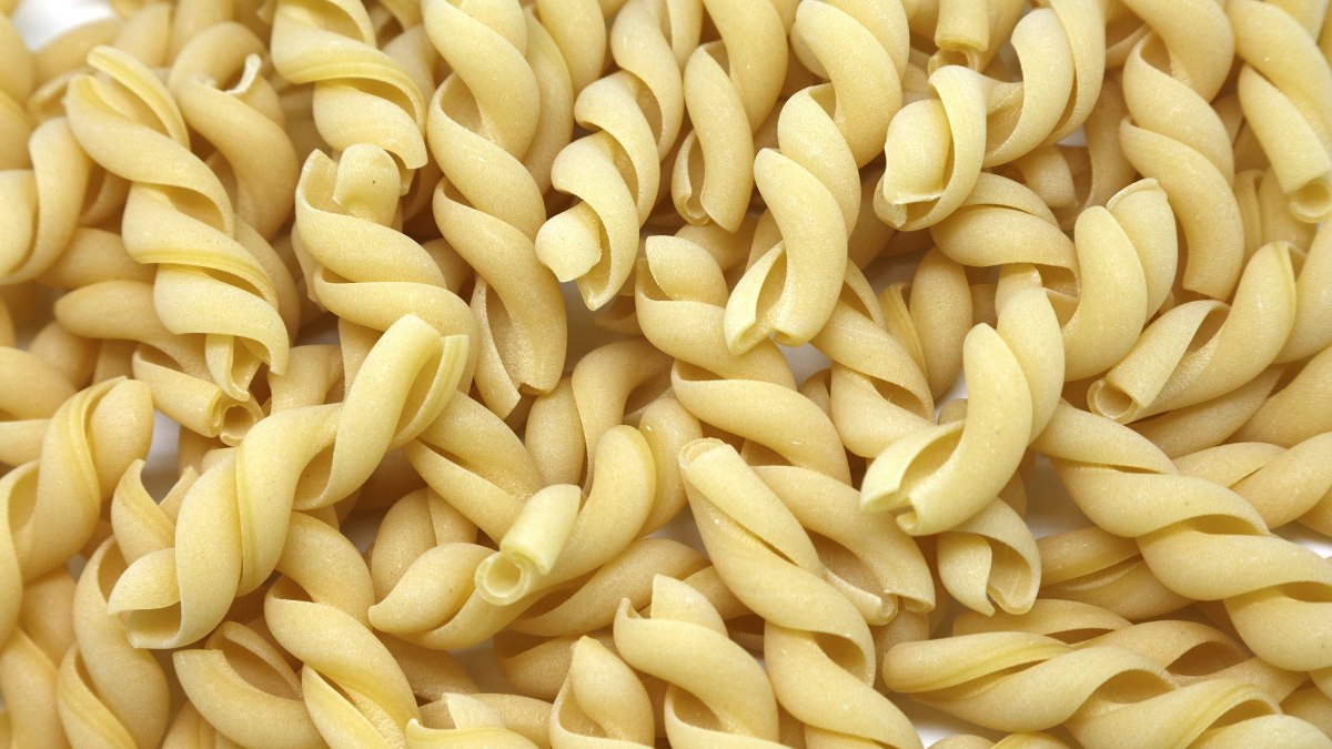 a pile of uncooked macaroni shells on a white surface.