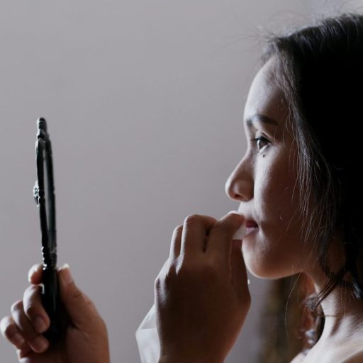 a woman holding a mirror up to her face.