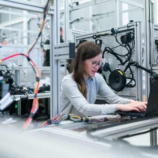 a woman working on a laptop in a factory.