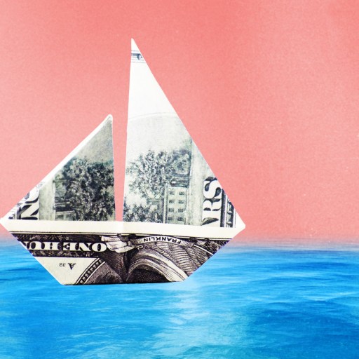 a dollar bill origami boat floating in the ocean.