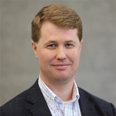 a man in a business suit smiling at the camera.