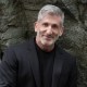 a man standing in front of a rock wall.