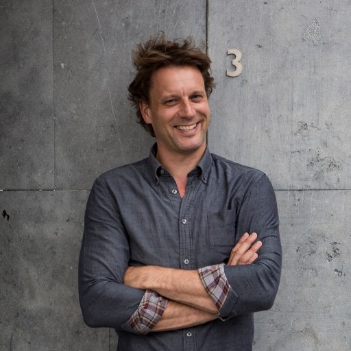 a man standing with his arms crossed in front of a wall.