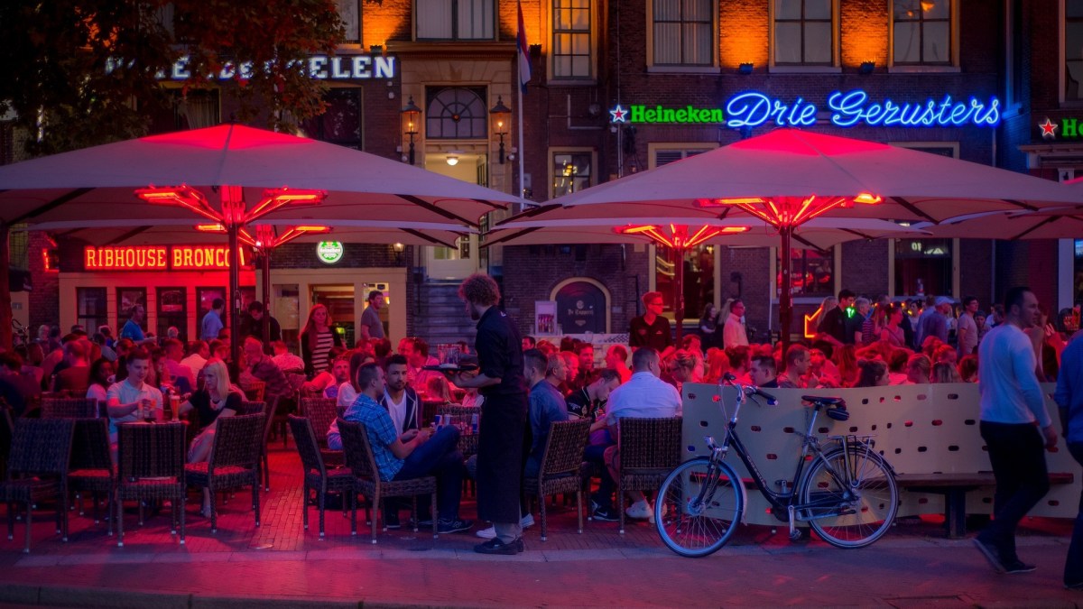 a group of people sitting at tables under umbrellas.