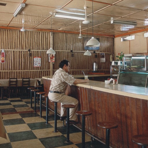 A man sitting at a counter in a restaurant with friends.