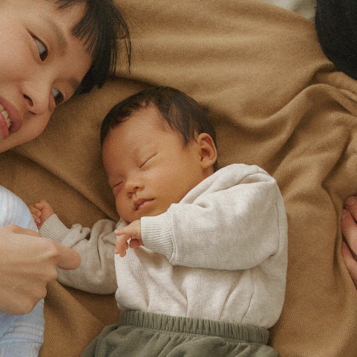 A man and woman laying on a bed with a baby.