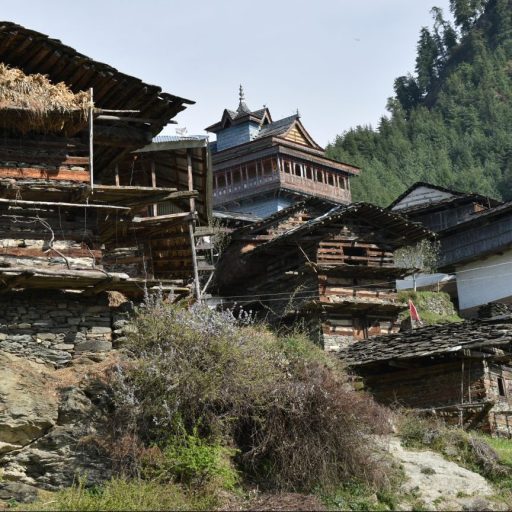 a group of wooden buildings sitting on top of a lush green hillside.