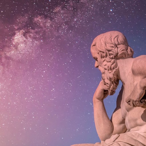 A statue of a man sitting under a night sky filled with stars.