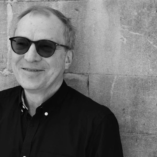 a man wearing sunglasses leaning against a wall.