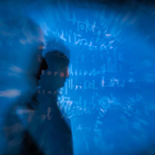 a blurry image of a man standing in front of a blue background.