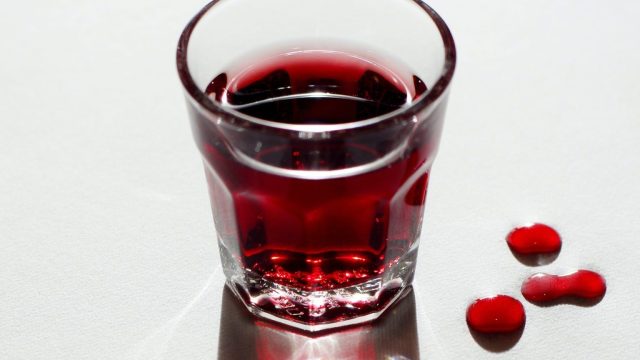 a glass of red liquid sitting on top of a table.