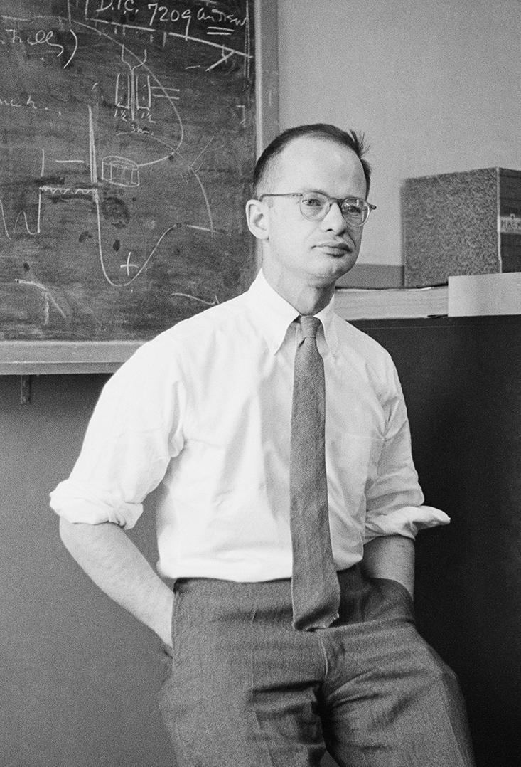 a man standing in front of a blackboard with writing on it.