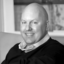 a bald man in a black shirt and tie.