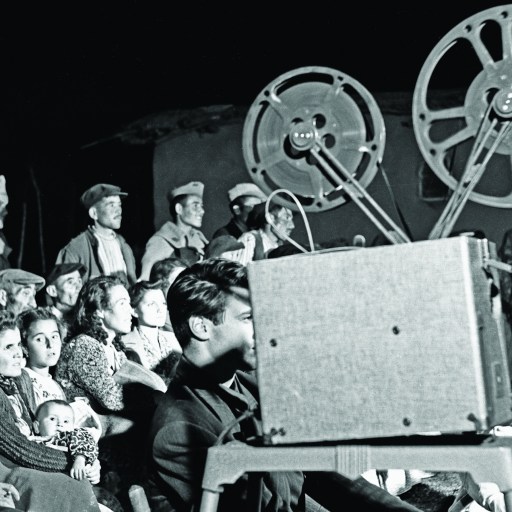 a black and white photo of a crowd of people watching a movie.