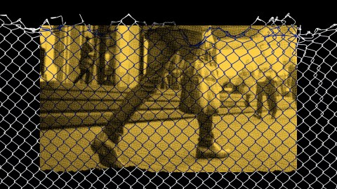 a black and white photo of a person behind a fence.