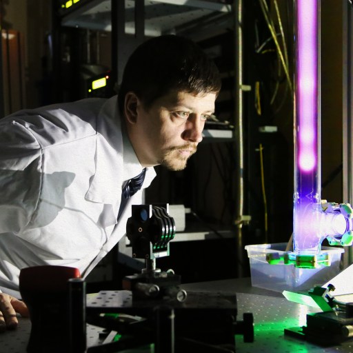 a man in a lab coat looking at a machine.