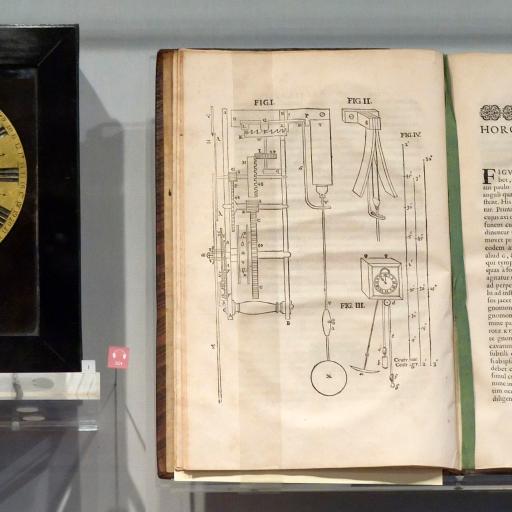 A clock, believed to be the first in America, showcased beside a book.