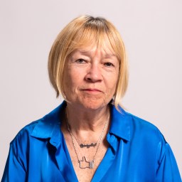 A woman in a blue shirt is posing for a photo.