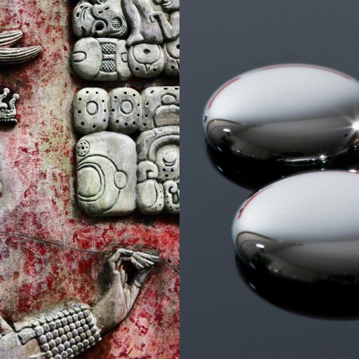 A group of silver balls resembling mercury surrounding a statue of a man influenced by Maya culture.