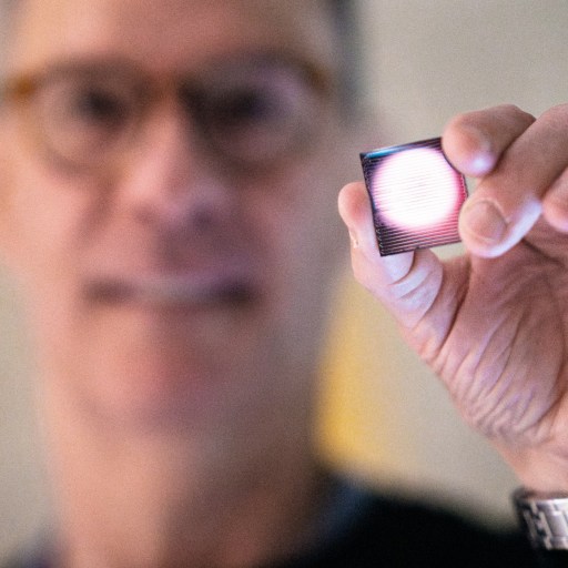 A man is holding up a small device for seizure detection.