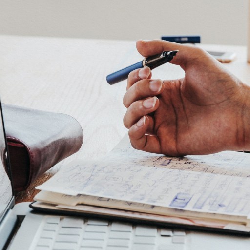 A post-career world with a desk holding a laptop and hand holding a pen.