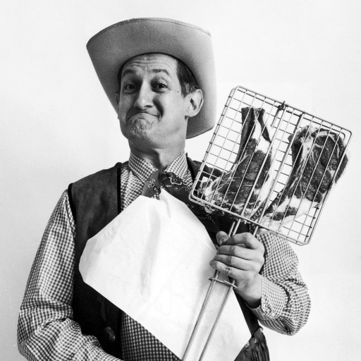 A man in a cowboy hat holding a chicken.