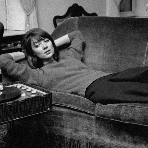 A woman with a music personality enjoying a record player on a couch.