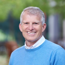 A smiling man in a blue sweater.