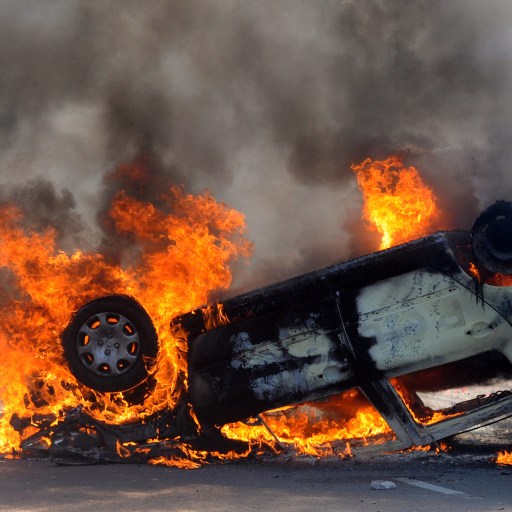 A burning car on the side of the road.