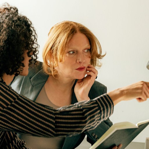 Two women demonstrating authentic leadership while conversing at a desk.