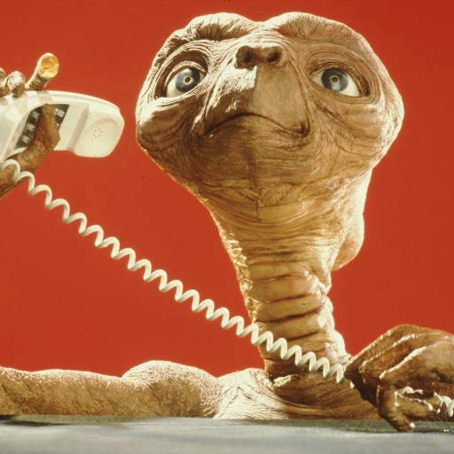A little alien talking on a telephone.