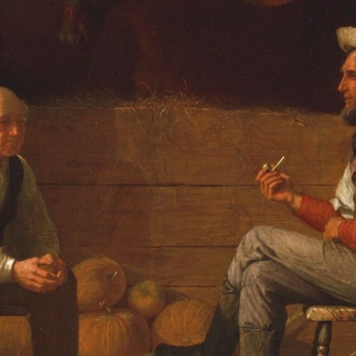 Two men sit facing each other in a barn with pumpkins behind them; one man holds a pipe, and both appear to be engaged in conversation.