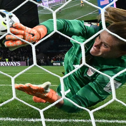 A soccer goalkeepers is diving to save a ball.