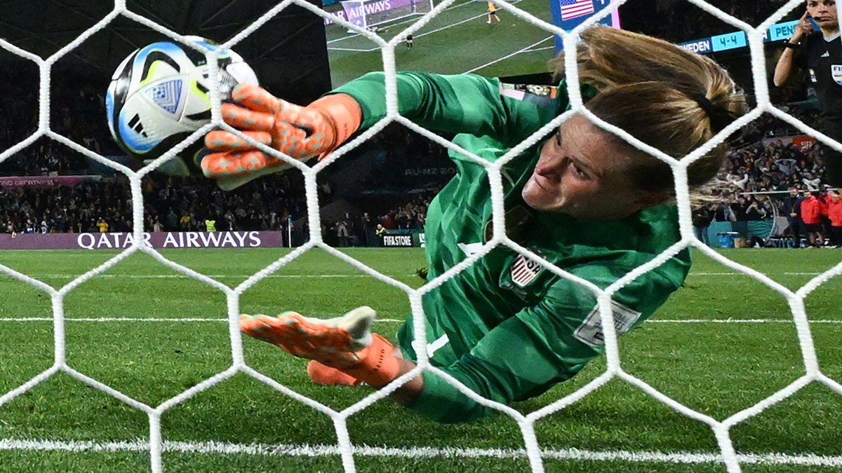 A soccer goalkeepers is diving to save a ball.