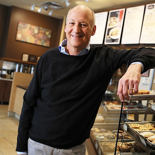 A man standing in front of a display of pastries at Panera Bread.