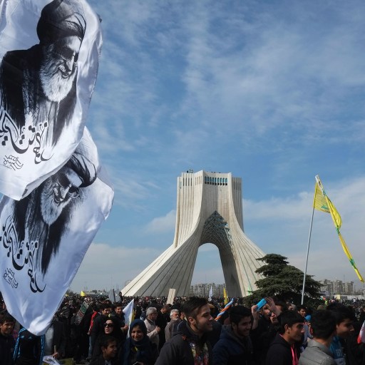 A group of people are holding flags in front of a monument representing democracy.