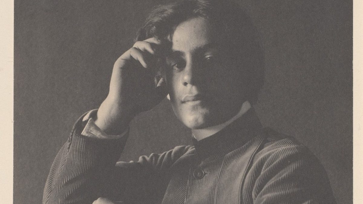 A black and white photo of a man with his hand on his head.