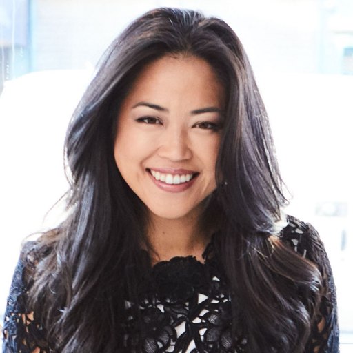 An asian woman smiling in front of a window.