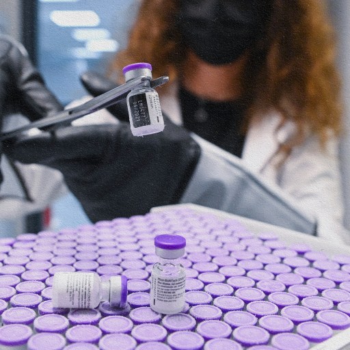 A woman holding a syringe administers an mRNA vaccine with gloves and a mask on.