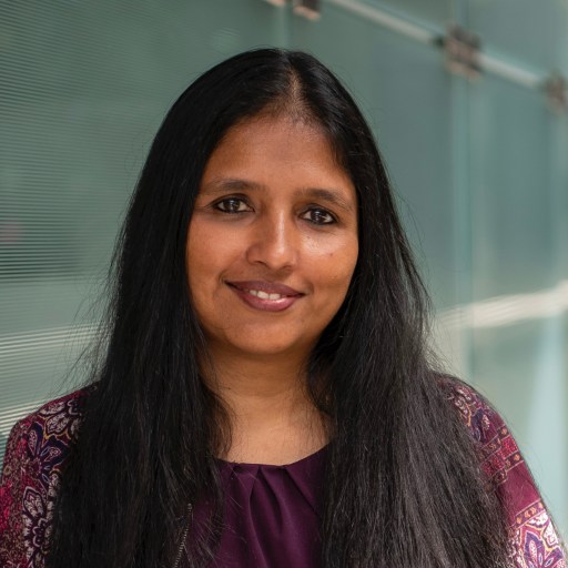 A woman with long black hair standing in front of a glass wall.