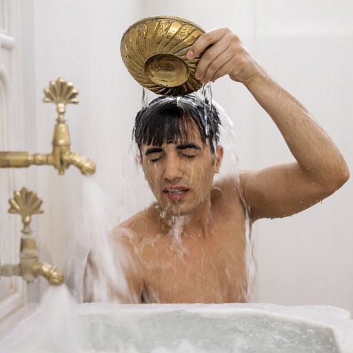 A man is taking a bath in a Thermae Romae-style bathtub.