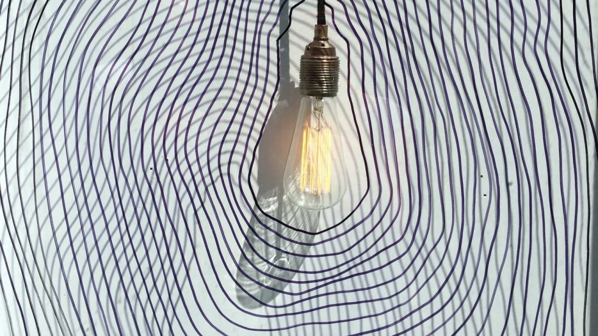 A light bulb hanging on a wall with a swirl pattern.